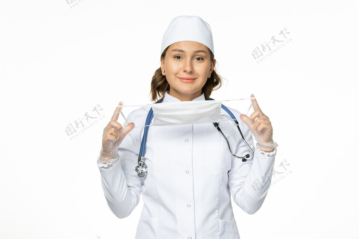 医疗正面图女医生身穿白色医疗服手持口罩在白墙上大流行疾病药物病毒隔离听诊器制服女性
