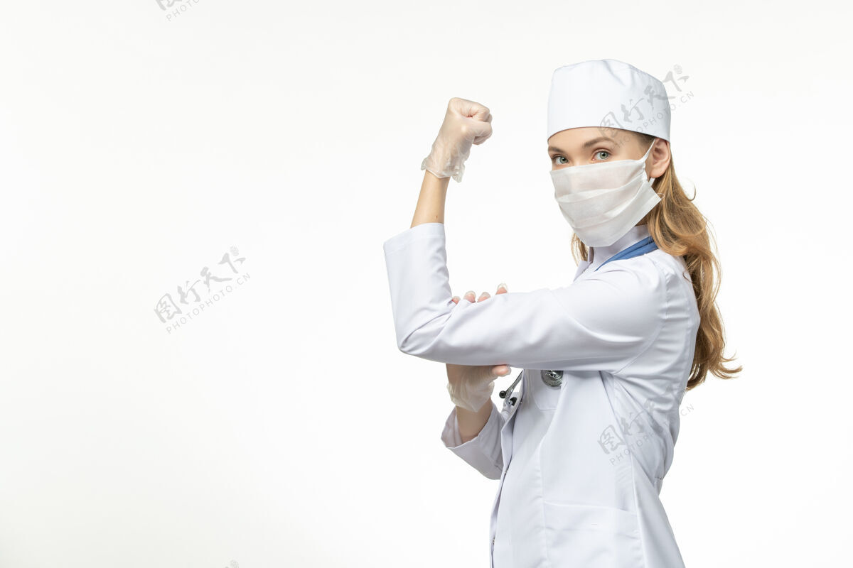 套装前视图：女医生穿着医疗服 戴着口罩和手套 因冠状病毒在轻白壁上弯曲而感染流行性冠状病毒女性人专业