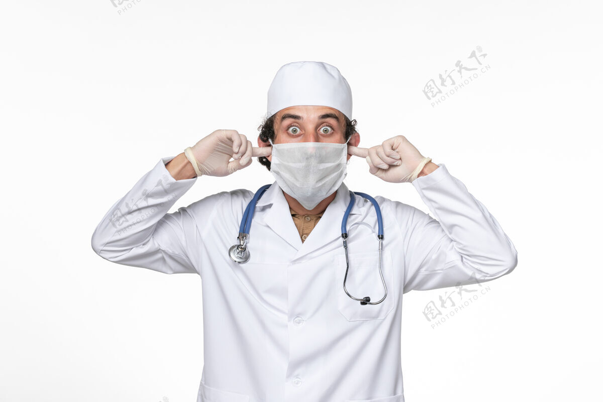 护目镜正面图：男医生穿着医疗服 戴着口罩 用白色办公桌上的冠状病毒大流行药物保护耳朵不受感染面罩冠状病毒病毒