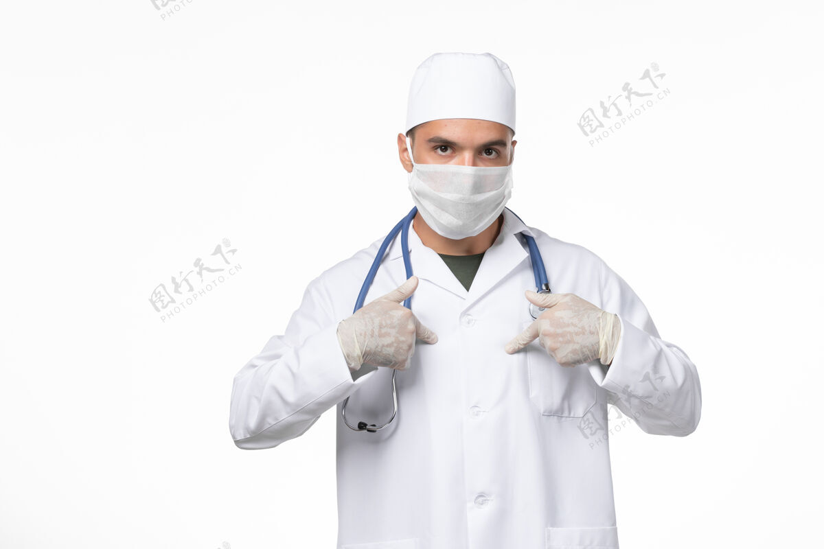 冠状病毒正面图：男医生穿着医疗服 戴着防毒面具-白色办公桌上的防毒药物-病毒大流行疾病大流行病毒视图