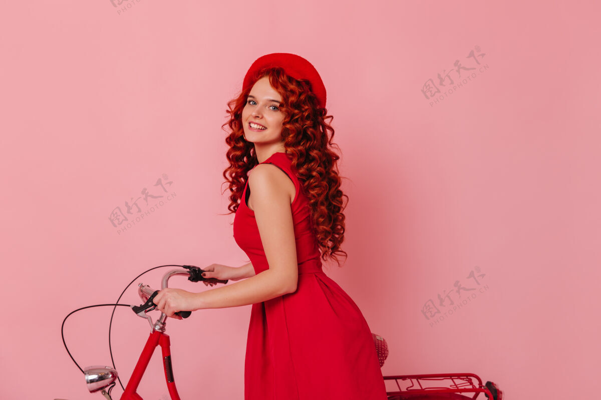 天后蓝色眼睛 戴着红色贝雷帽的漂亮女人的肖像穿着裙子的红发女孩在粉色空间和自行车合影自行车魅力头发