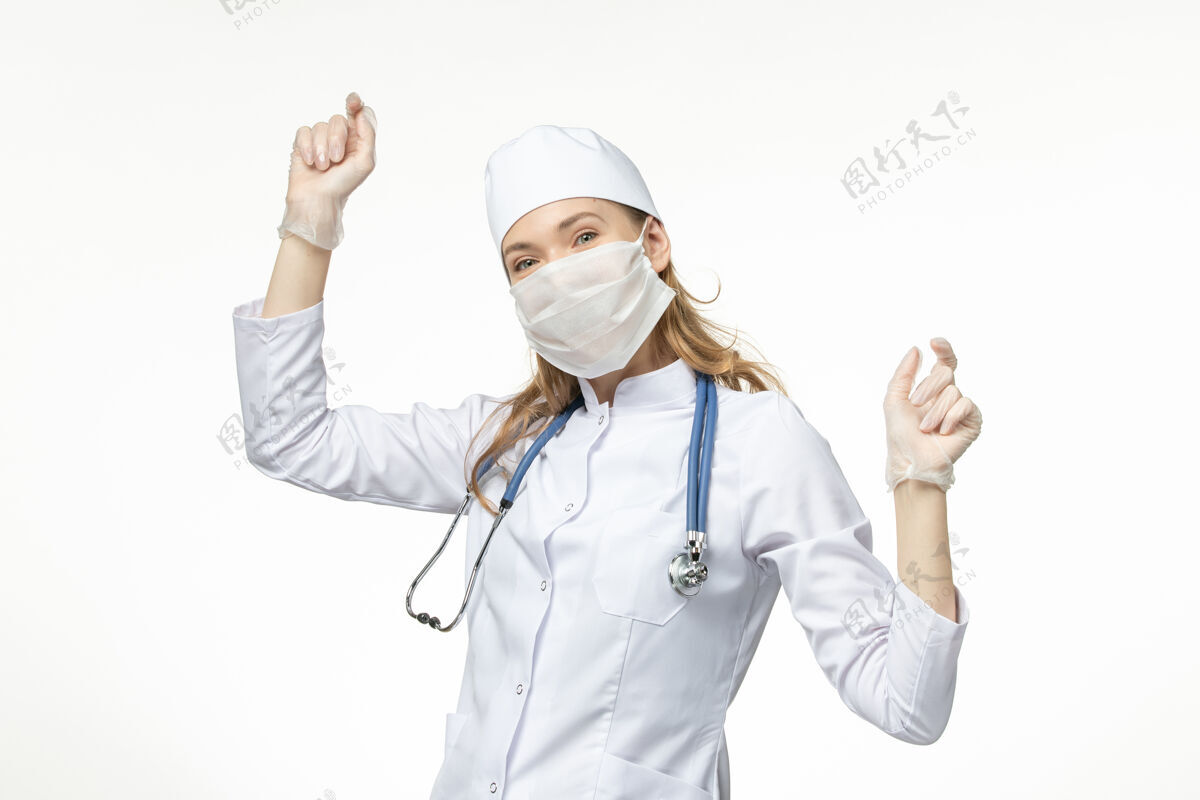 舞蹈正面图女医生穿着医疗服带着无菌口罩因冠状病毒在白墙上跳舞疾病大流行健康冠状病毒听诊器冠状病毒防护护士