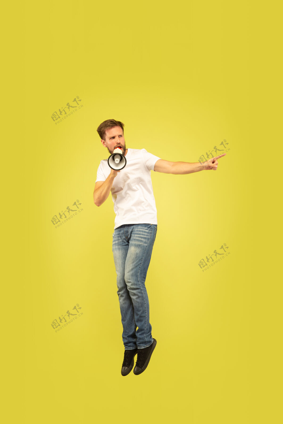 跳跃黄色背景上孤立的快乐跳跃人的全长肖像穿着休闲服的白人男模充分手运动