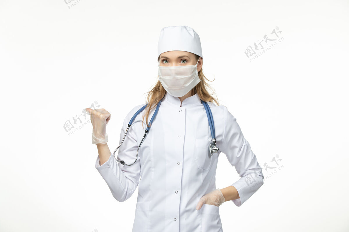 医生正面图女医生穿着医疗服 带着无菌口罩 因白墙上有冠状病毒病大流行性疾病冠状病毒到期医疗冠状病毒防护
