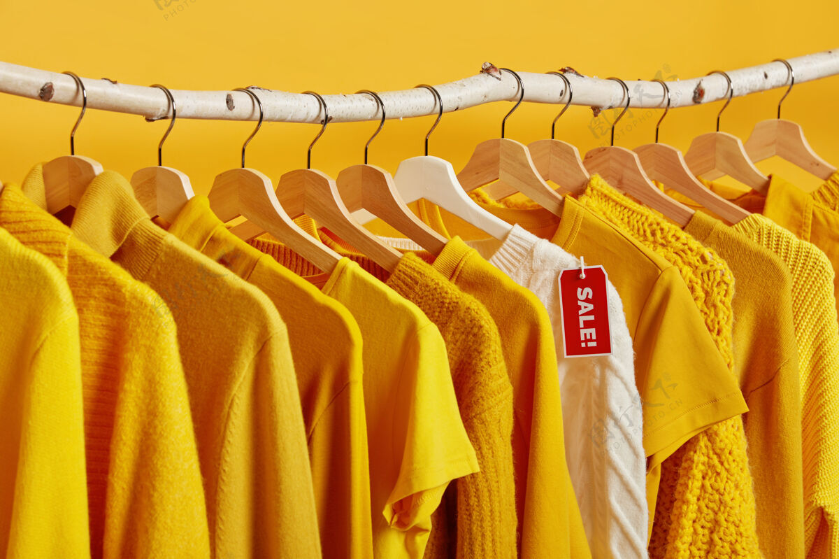 衣服黄色和白色的衣服挂在货架上 背景生动大减价和购物套头衫衣架白色
