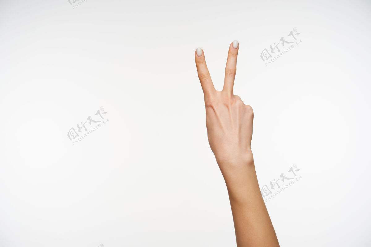 符号特写在年轻的精心打扮的妇女的手被举起 同时形成胜利的姿态手势皮肤站
