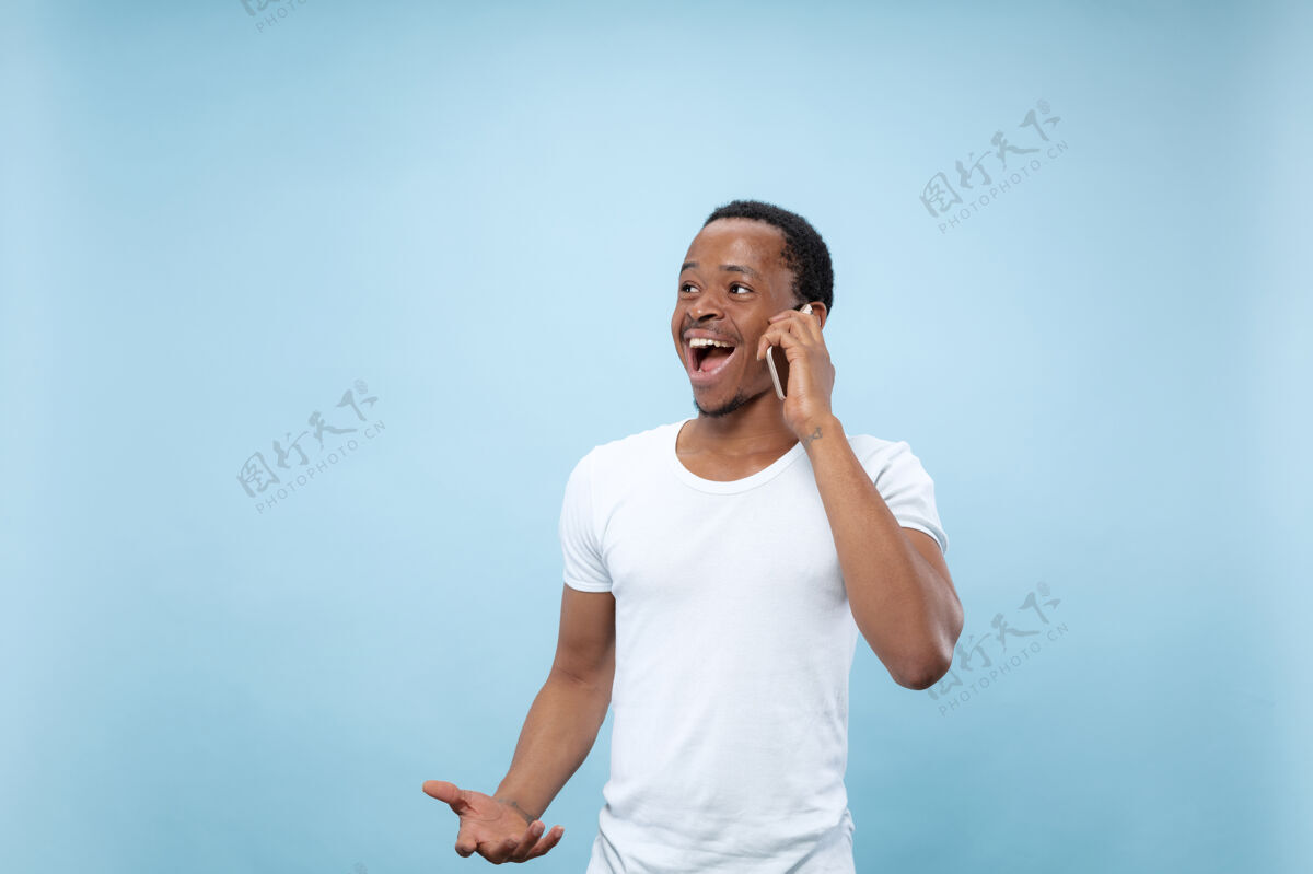 手势半身特写肖像的年轻非洲裔美国男子在白色衬衫的蓝色空间人类的情感 面部表情 广告概念就业男人选择