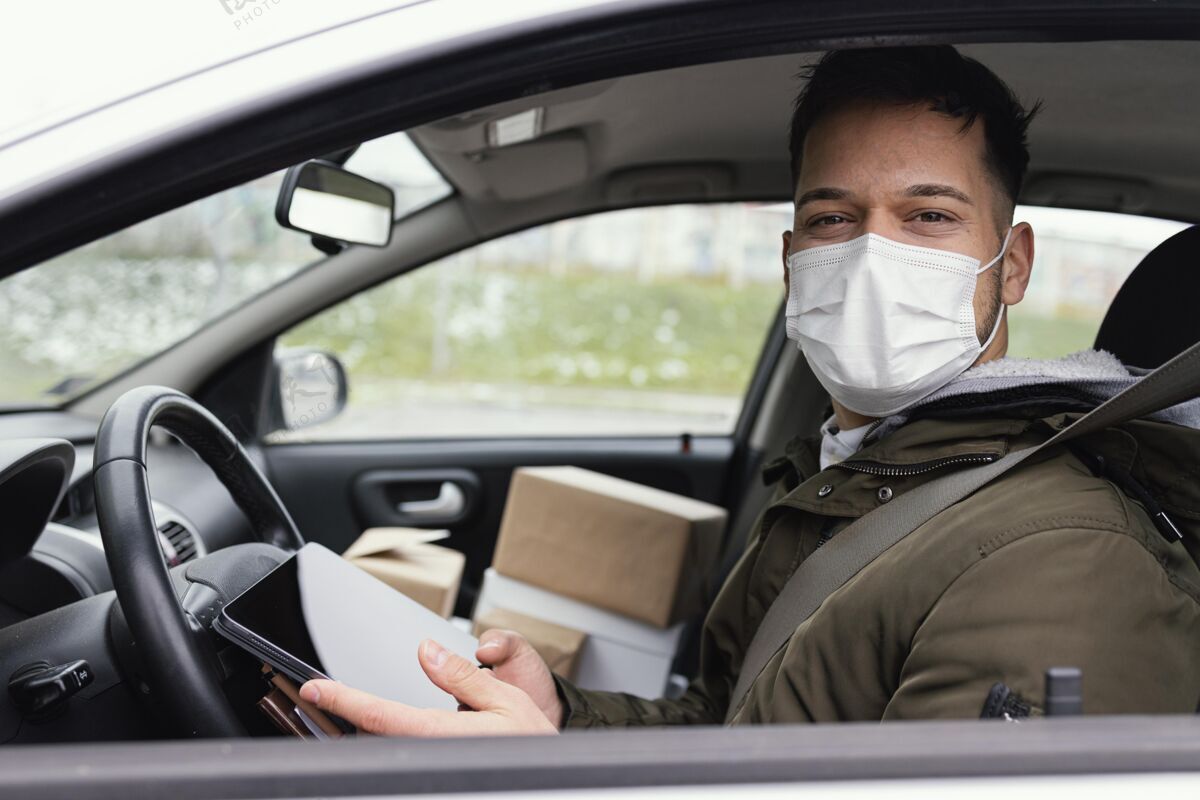 男带着面具和包裹的男性送货员送货服务电话汽车