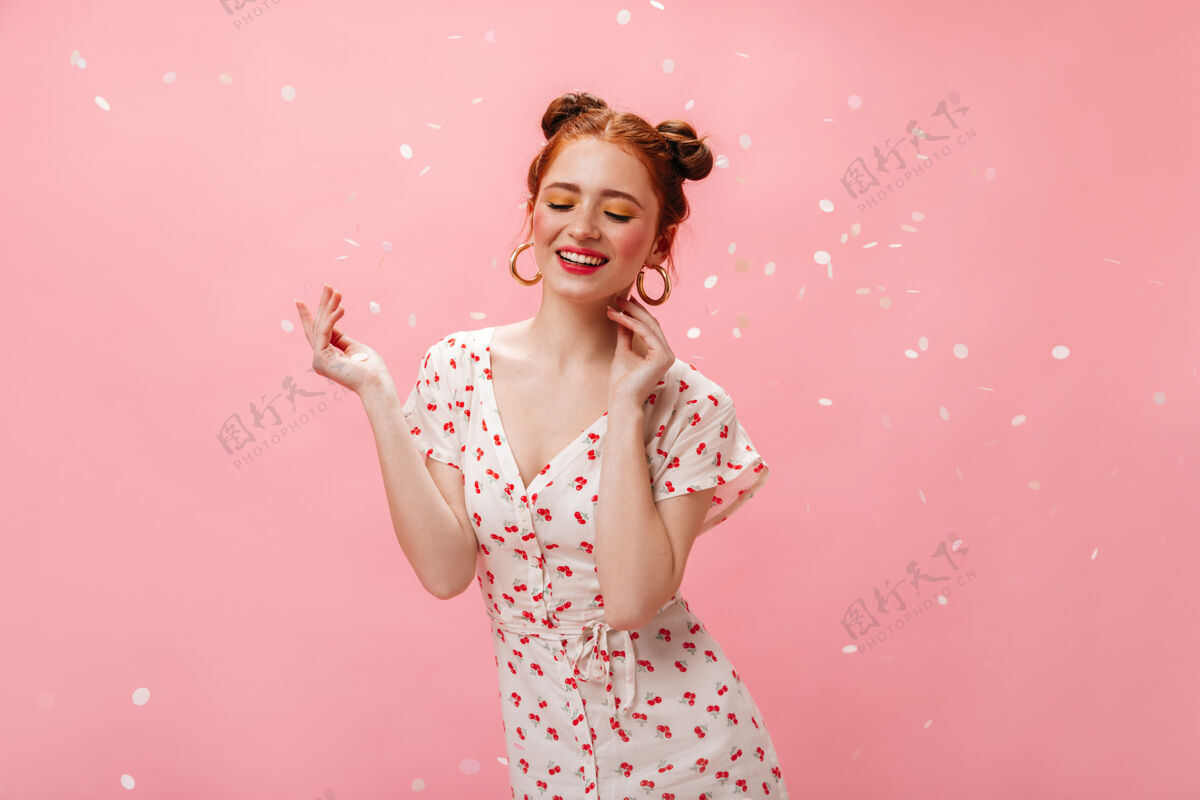 乐趣迷人的白裙樱桃女士微笑着和蔼可亲在粉红色背景上的大耳环红发女子肖像模特漂亮肖像