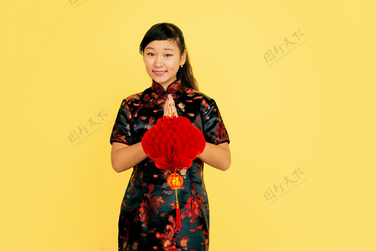 传统带着灯笼 微笑着 谢谢中国新年快乐黄色背景上的亚洲少女肖像身着传统服装的女模特看起来很快乐复制空间服装中国女性