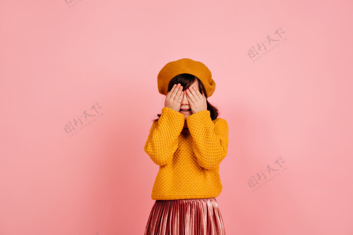 乐趣孩子把脸藏在粉红色的墙上孩子毛衣时尚