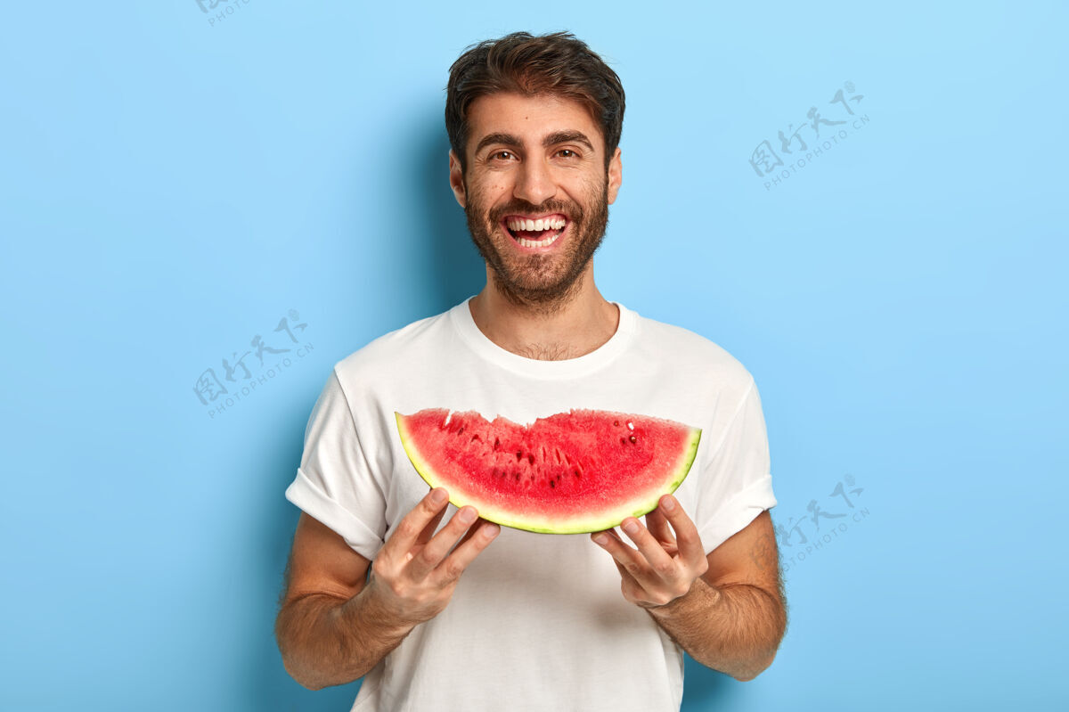 快乐夏日里抱着一片西瓜的微笑男人的腰间照西瓜营养水果