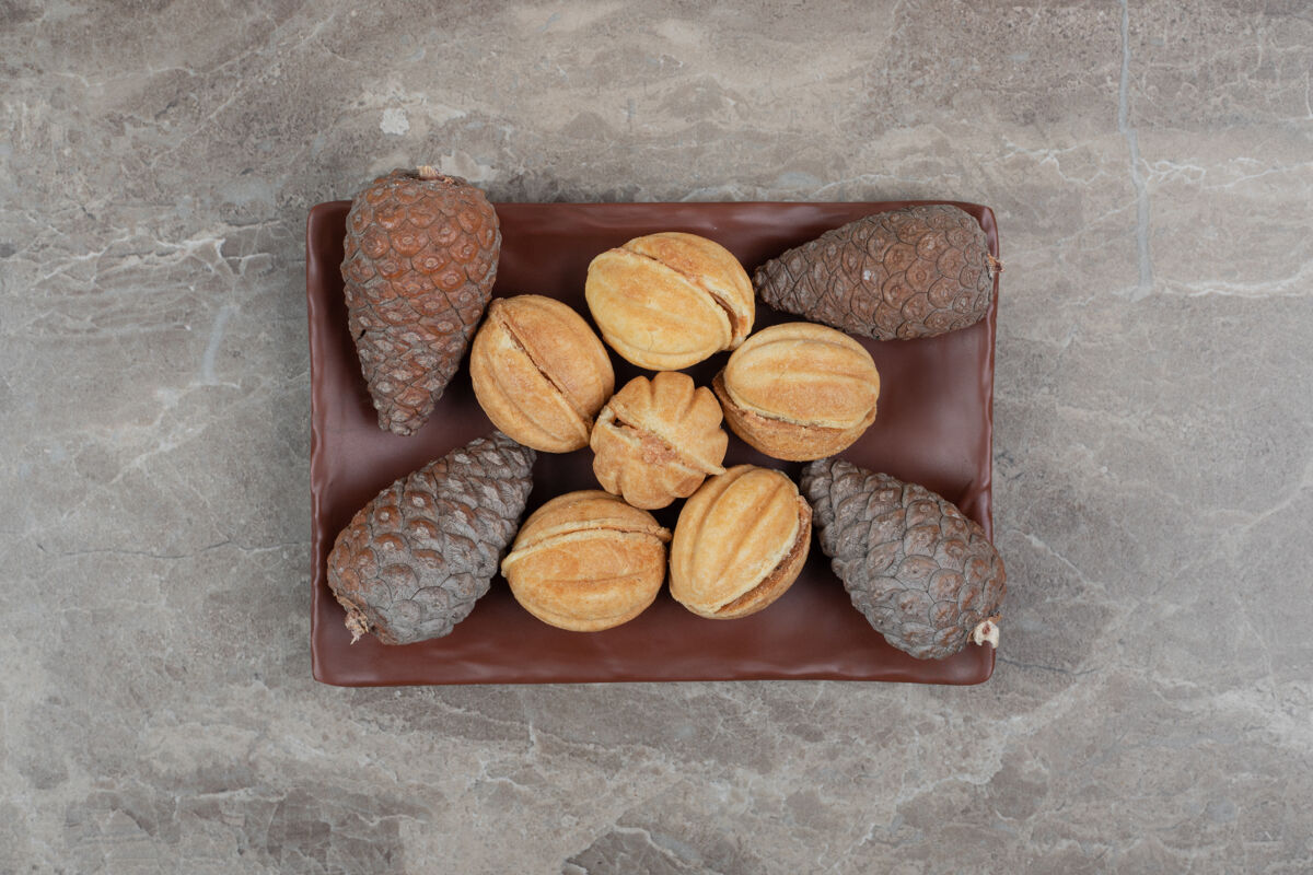 饼干核桃形状的饼干和松果放在深色的盘子里高质量的照片坚果焦糖面包房