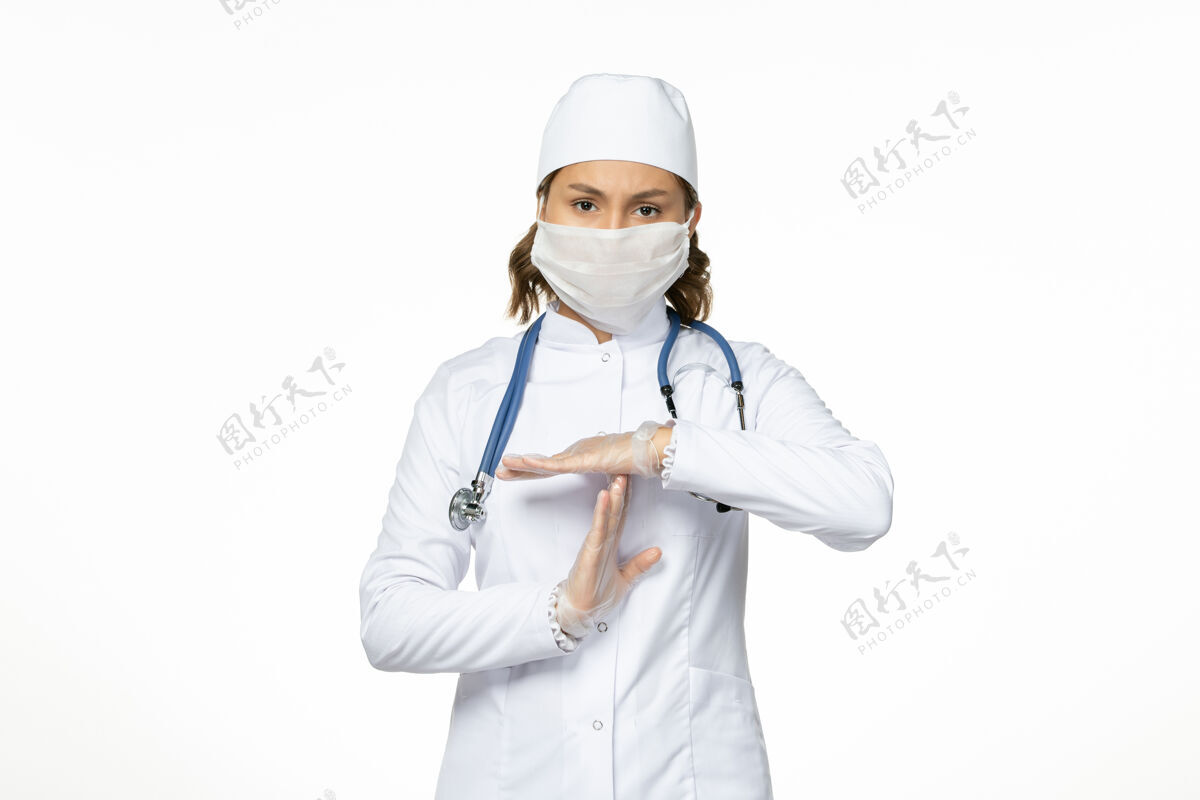 面罩正面图年轻女医生 身穿白色医疗服 浅白色办公桌上戴着冠状病毒口罩套装到期专业