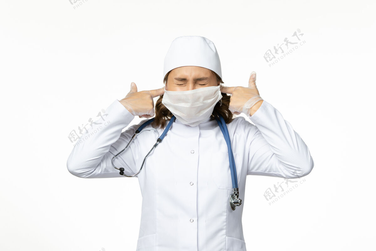 病毒正面图年轻女医生戴着防护口罩 因为冠状病毒把耳朵关在了白色的表面上冠状病毒女性大流行