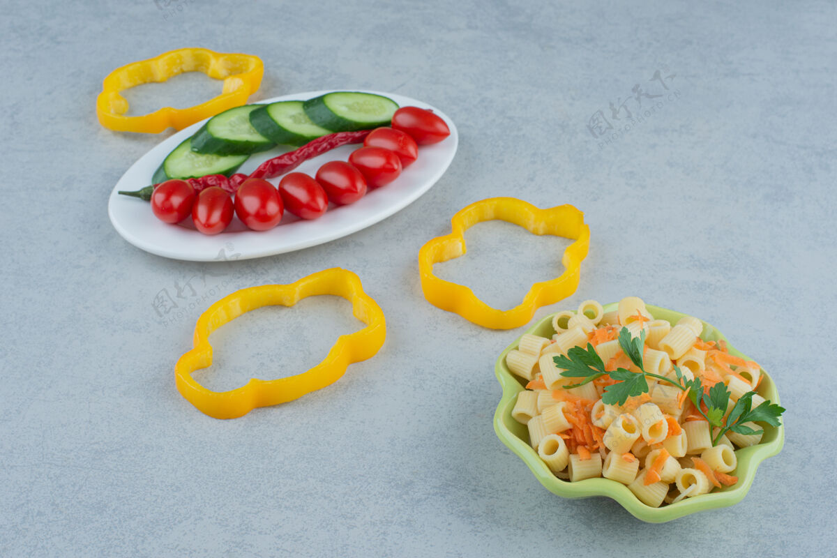 食物白色盘子上的蔬菜沙拉和大理石背景上的通心粉高品质照片胡椒番茄樱桃番茄