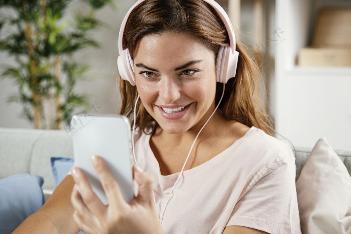 女人戴着耳机的女人用手机笑脸手机设备
