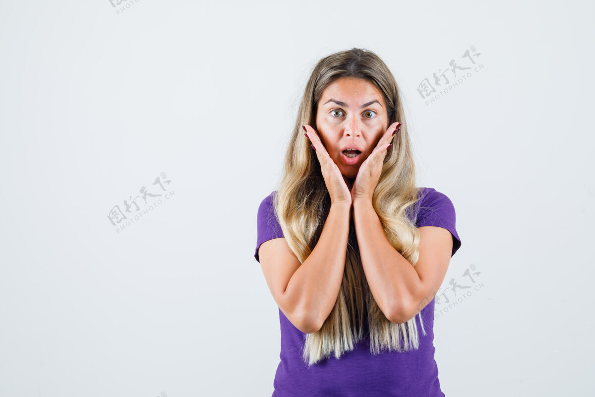 黑发身穿紫罗兰色t恤的年轻女士手拉着手 张大了嘴巴 看上去很震惊 正对着前方女人外观时尚