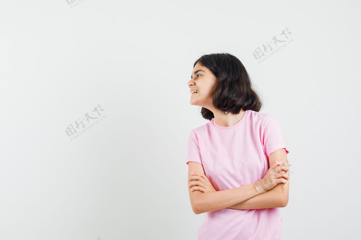 美丽小女孩交叉双臂站在粉红色t恤衫上 看起来很欢快 正面视图手臂欢快青少年