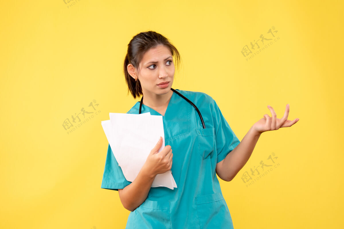 医学正面图年轻的女医生穿着医疗衬衫 黄色背景上有纸成人医学纸