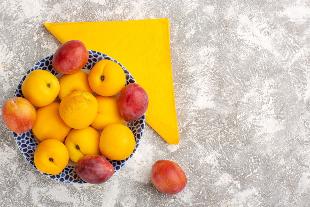 苹果顶视图新鲜甜杏黄色水果盘内与李子在白色表面水果食品盘子