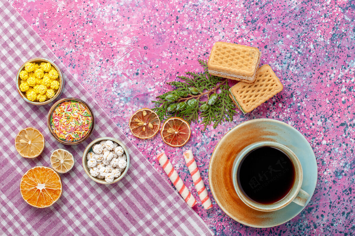 咖啡因在粉红色的桌子上放一杯茶和饼干 华夫饼和糖果杯子食品桌子