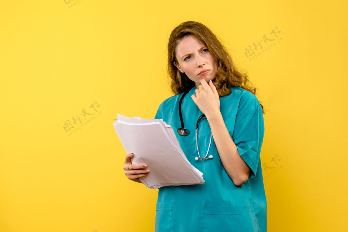 持有正面图年轻女医生拿着文件在黄色空间前面微笑医院