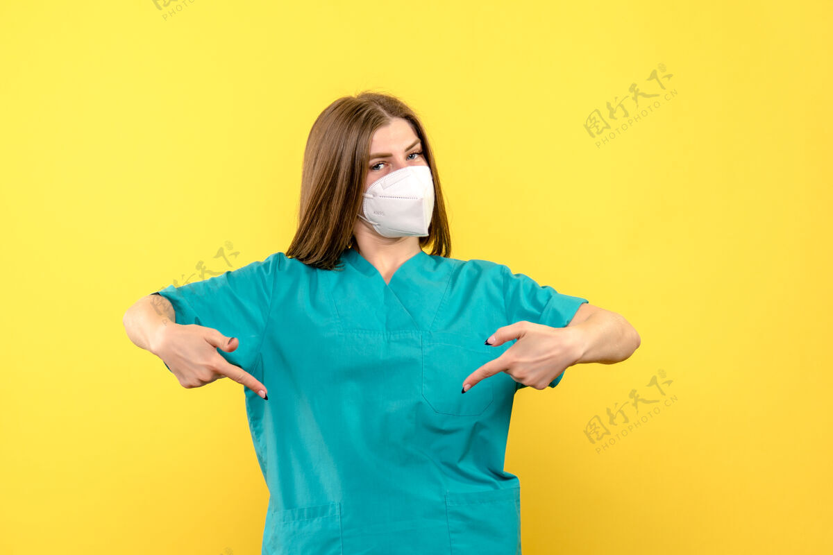 一个黄色空间上戴面罩的女医生的正面图流行前面站