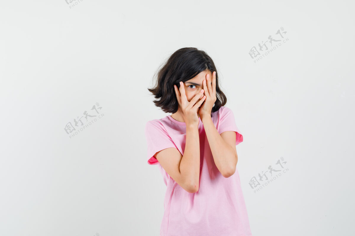 时尚小女孩穿着粉色t恤透过手指看 很好奇的样子 前视图和平休闲通过