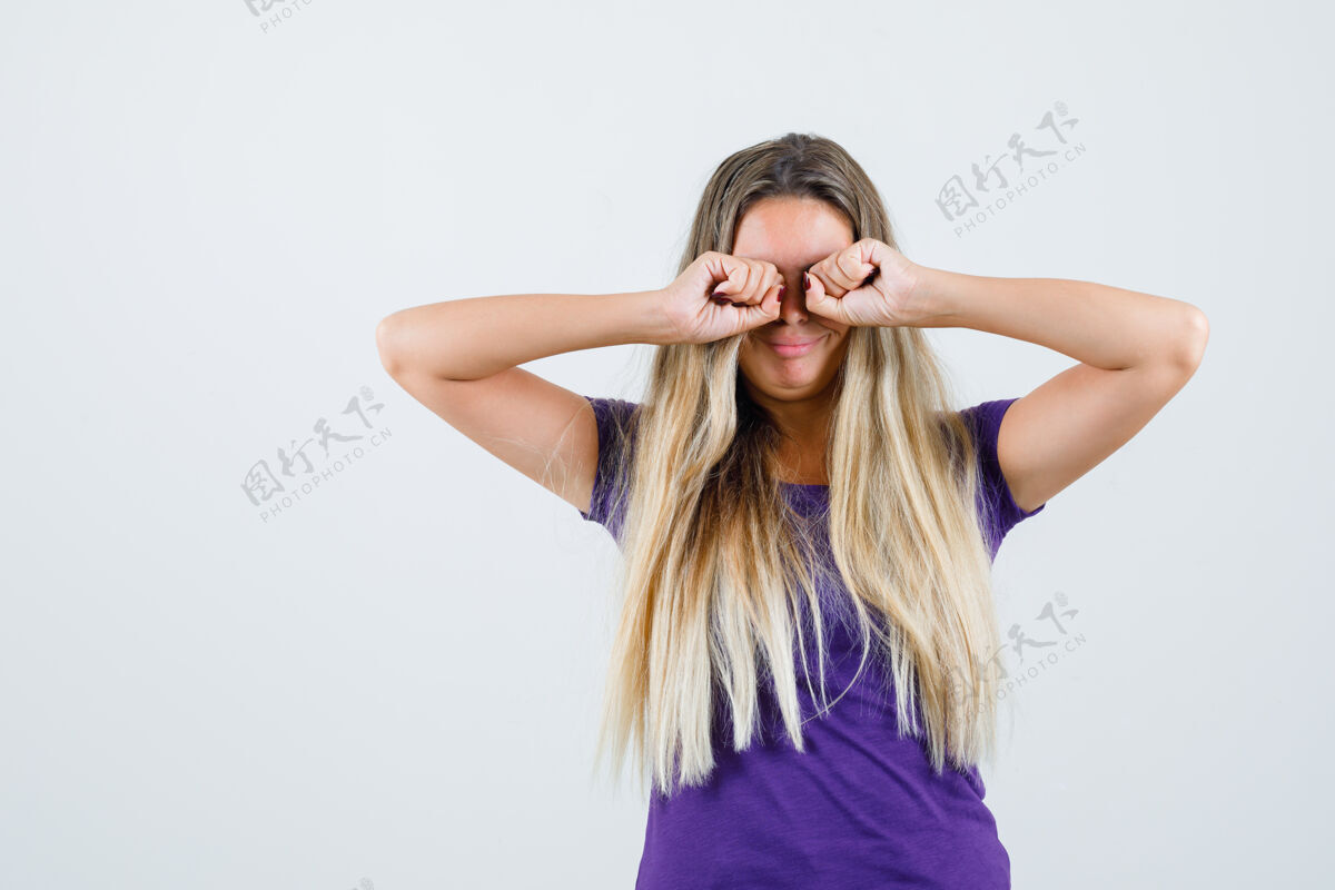 可爱一个金发女人穿着紫罗兰色的t恤边哭边揉眼睛 看起来很生气 正面视图金发时尚年轻