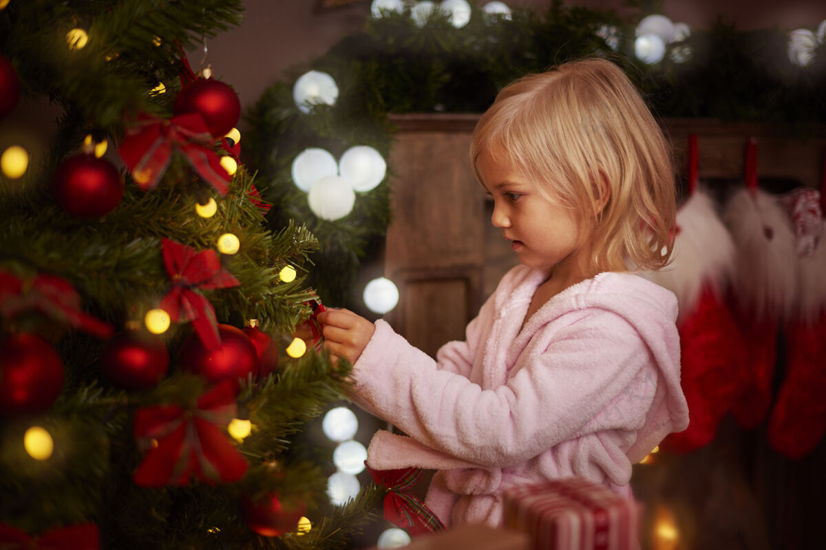 魔术小女孩在装饰圣诞树庆祝蝴蝶结客厅