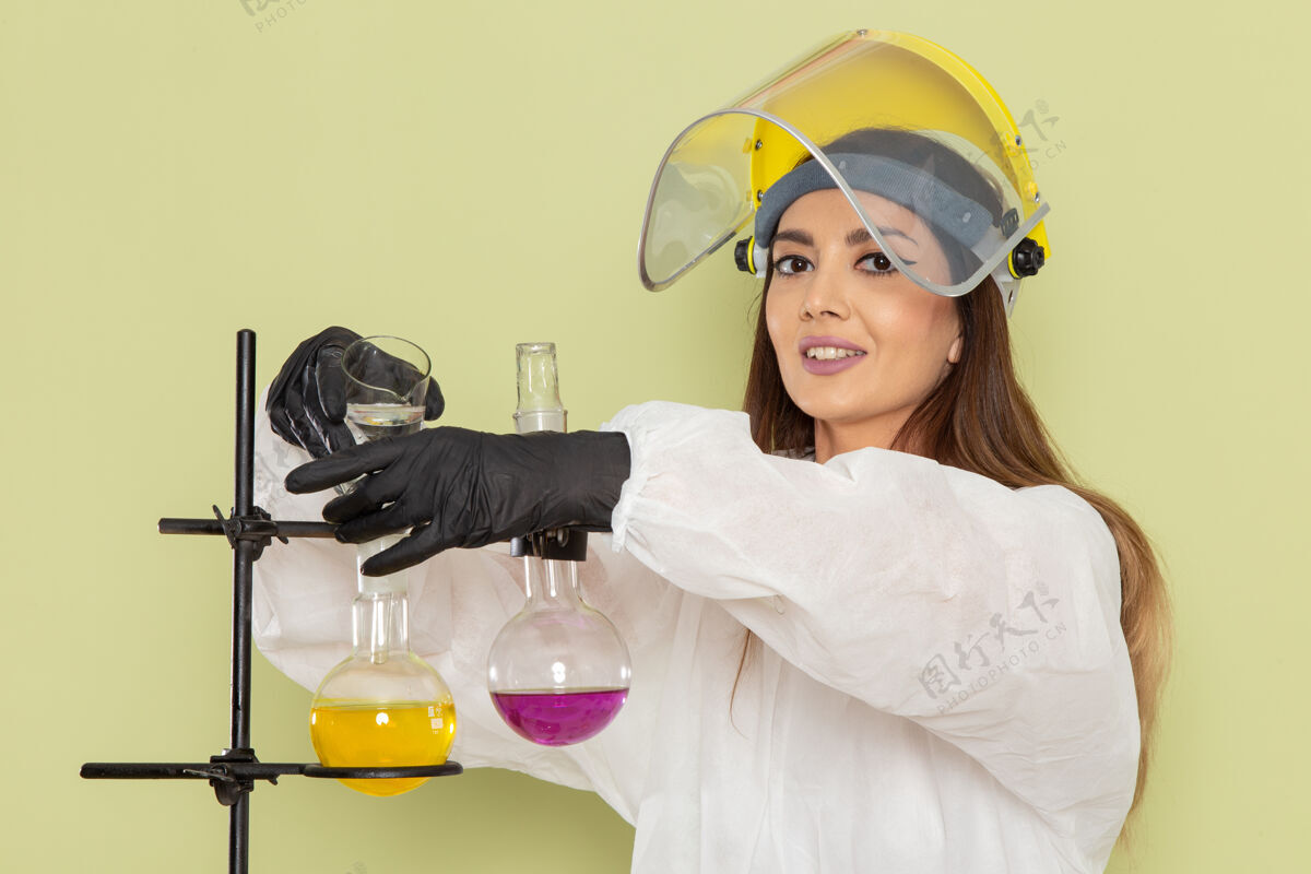 男人正面图身着特殊防护服的年轻女化学家在绿墙化学实验室工作化学工作女科学解决方案化学沙龙