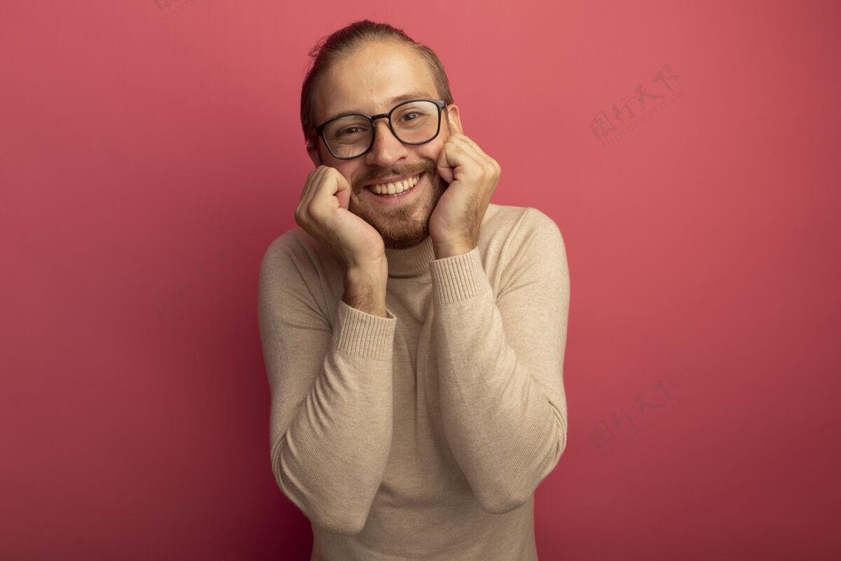 人身穿米色高领毛衣 戴着眼镜的年轻帅哥站在粉色的墙上 面带微笑 心情愉快地看着前方积极胡须男人