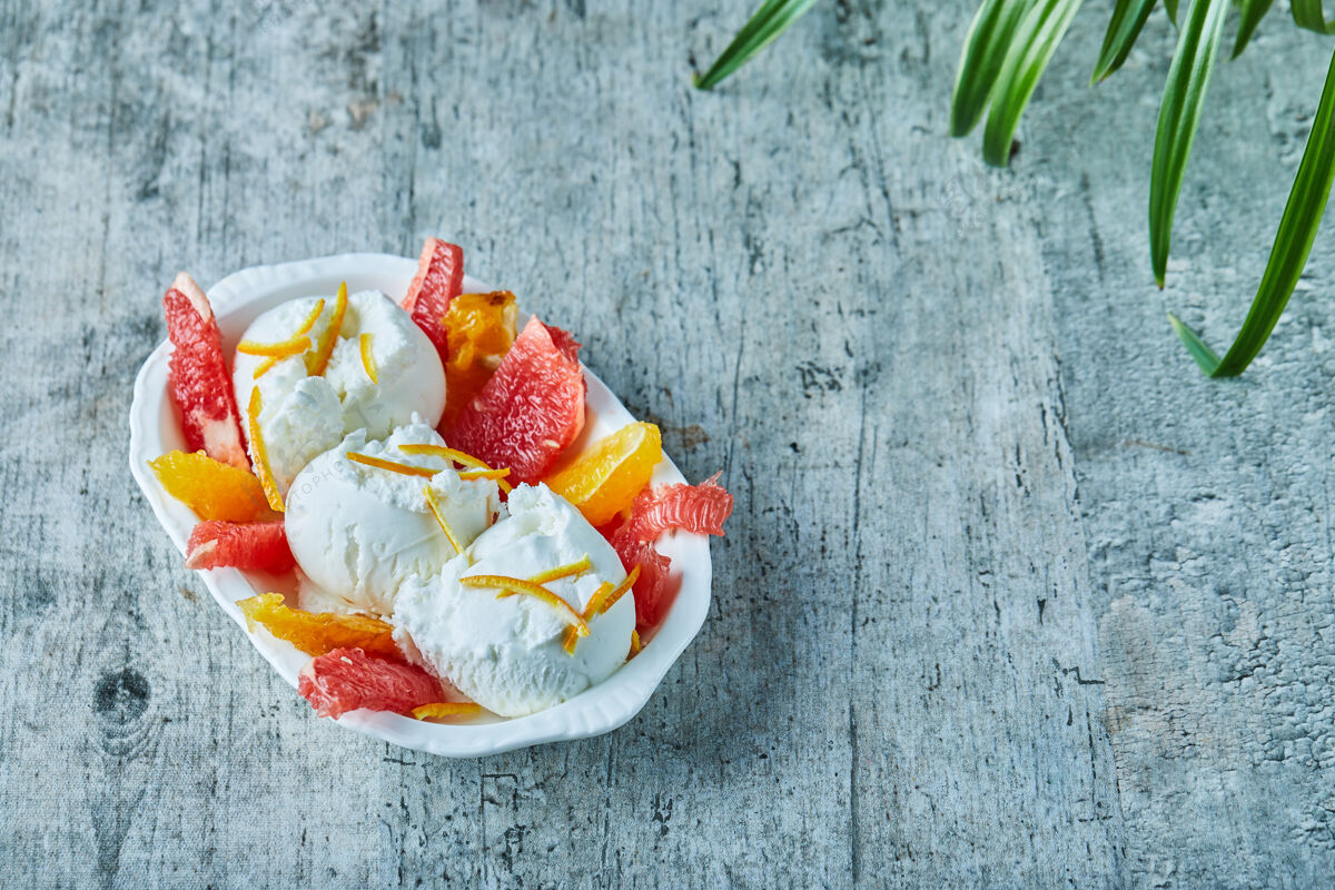 奶制品雪糕加葡萄柚和橘子片放在白碗里美味甜点水果