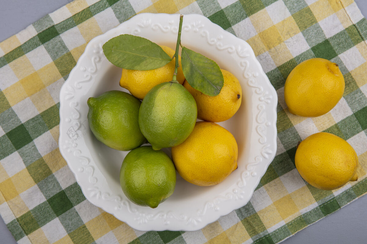 酸橙在黄色格子毛巾上的盘子里放着柠檬和酸橙黄色水果上衣