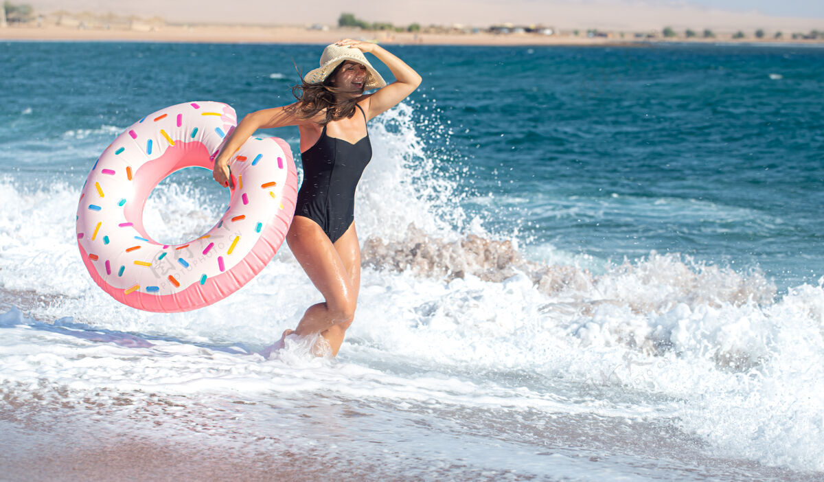 姿势一个快乐的年轻女子 在海边有一个甜甜圈形状的游泳圈度假休闲娱乐的概念女人大海日落