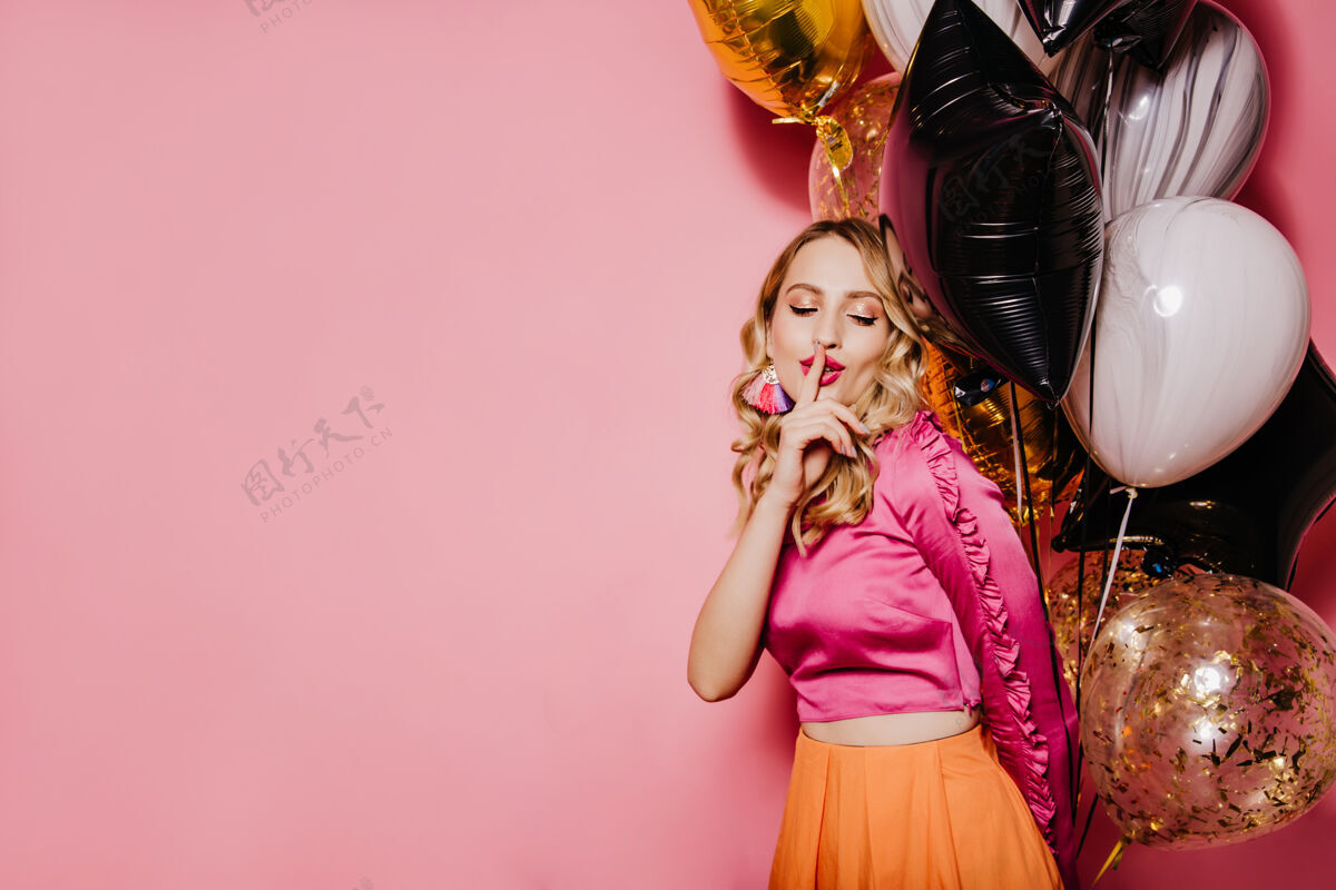 气球优雅的生日女人在粉红色的墙上摆姿势聚会周年纪念金发