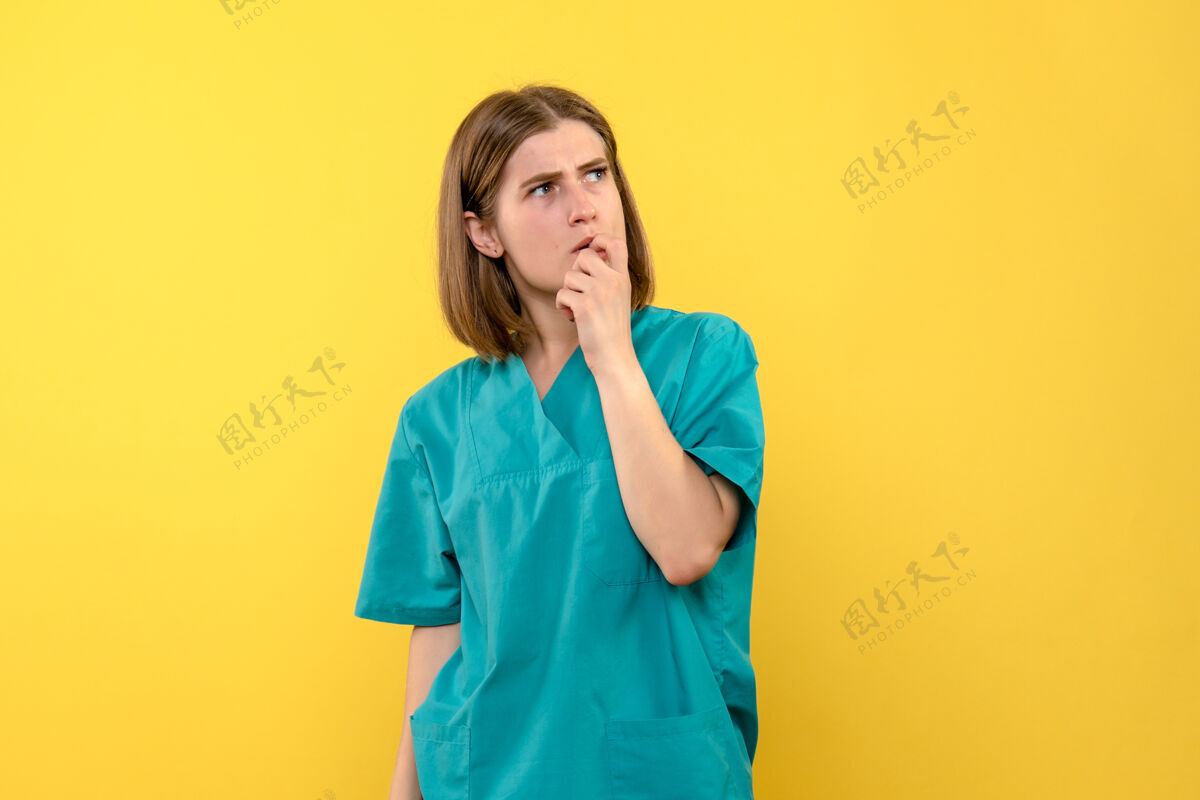 黄色黄墙上有思考表情的女医生正面图音乐家医院情感