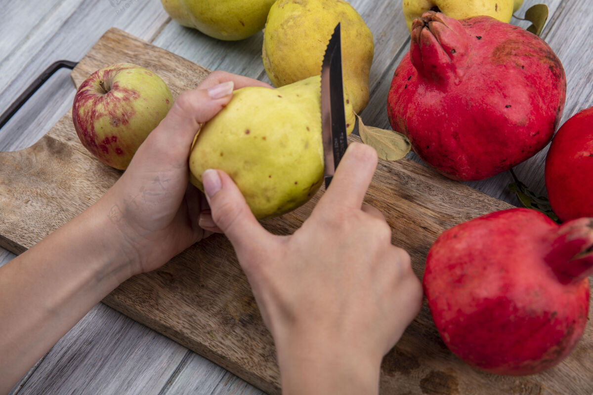 灰色俯视图中的女性手剥新鲜的木瓜在一个木制的厨房板上用刀在灰色的木制背景乡村木瓜顶部