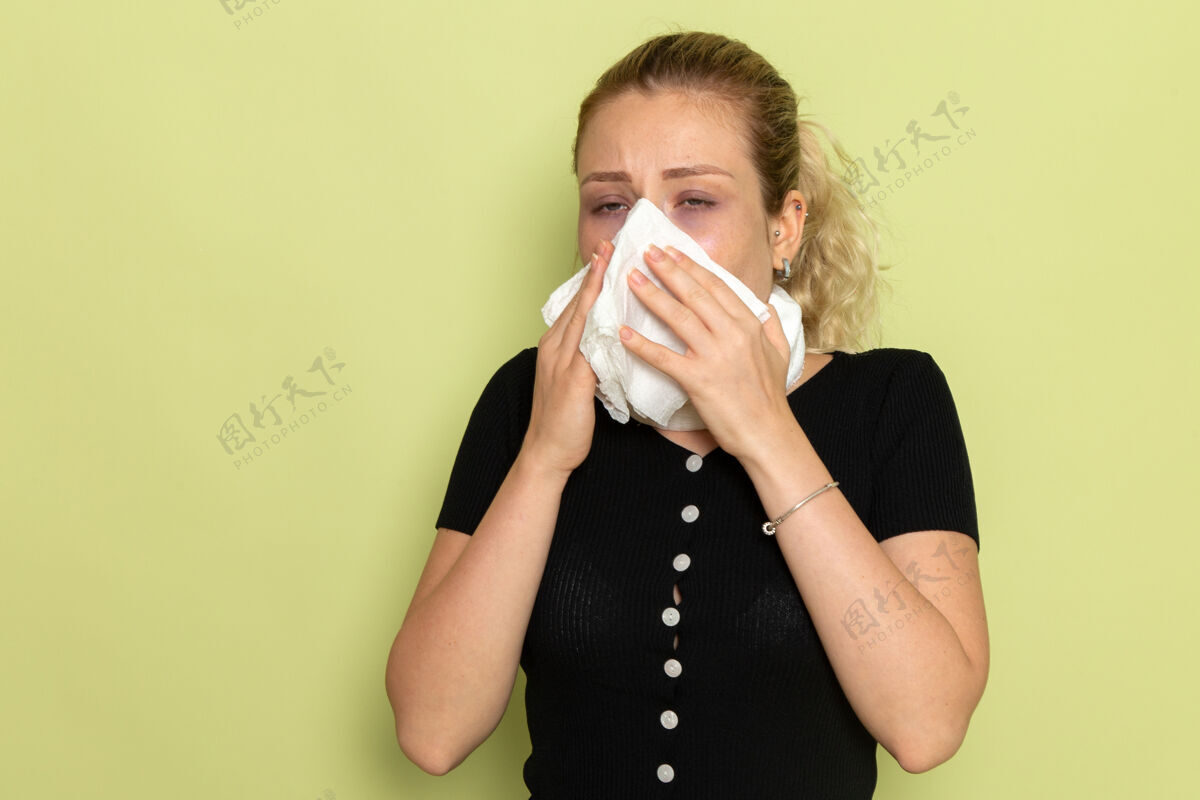 年轻人正面图年轻女性用白毛巾围住喉咙 感觉非常不舒服 在浅绿色墙壁上清洗鼻子生病生病女性健康感情喉咙浅绿色
