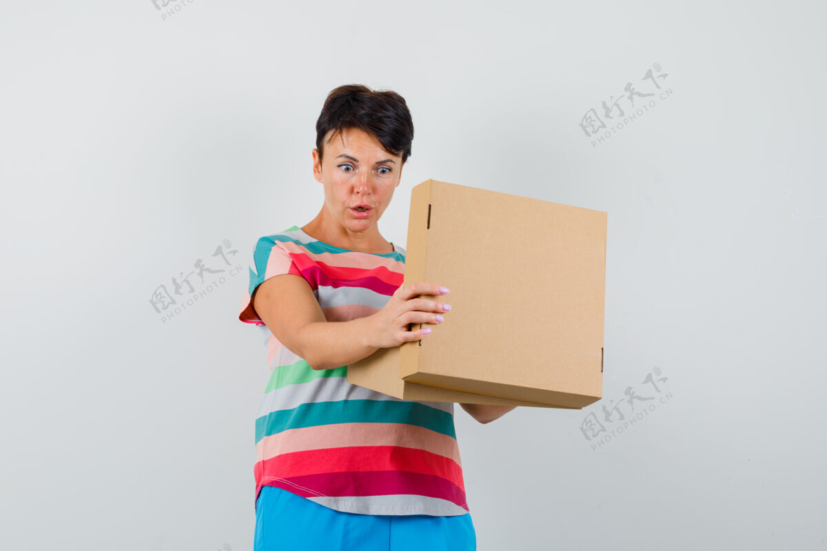 脸一个穿着条纹t恤和裤子的女人看着纸板箱 看起来很惊讶欢呼单身看