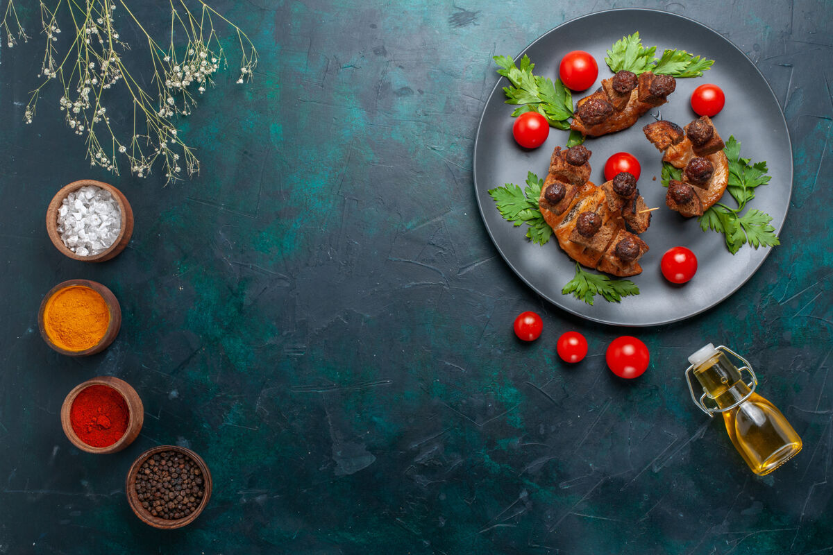肉俯瞰用橄榄油和调味料炒肉片上的深蓝色桌面蔬菜食品肉类健康餐晚餐橄榄胡椒