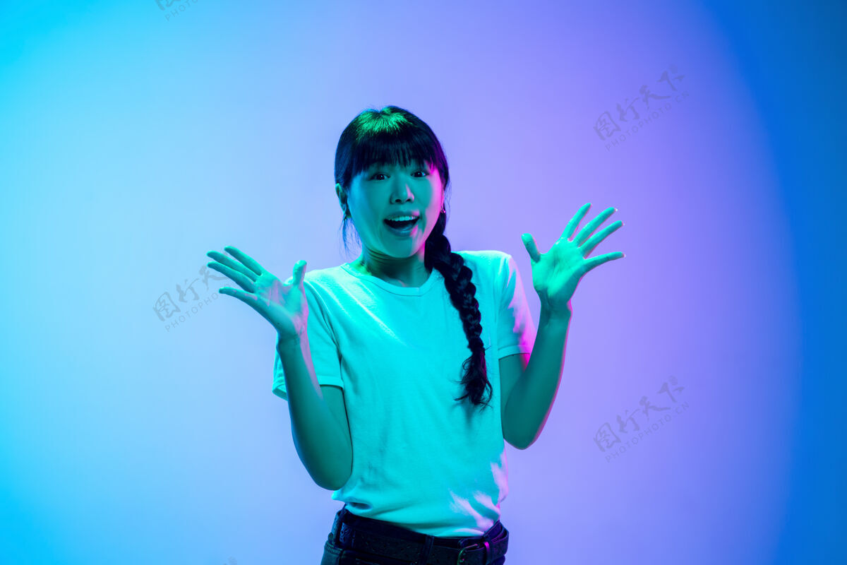 青年在霓虹灯下的渐变蓝紫色工作室背景上的年轻亚洲女性肖像青春概念 人类情感 面部表情 销售 广告美丽的深褐色模特设备时尚女孩