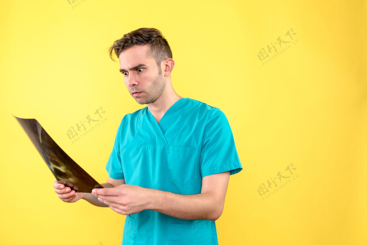 工作黄色地板上男医生手持x光片的正面图卫生院医护人员感慨黄色人肖像