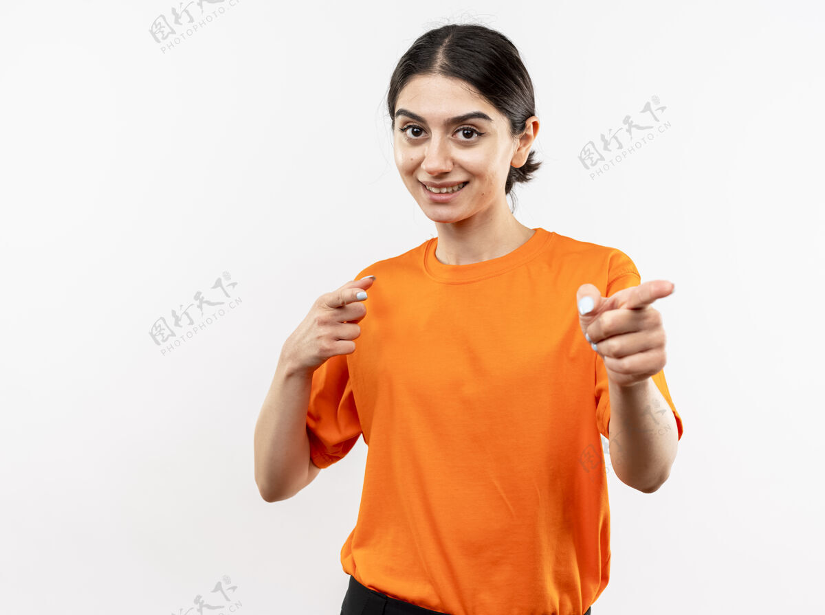 女孩穿着橙色t恤的年轻女孩 食指指着白色的墙壁 开心地笑着微笑橙色欢呼