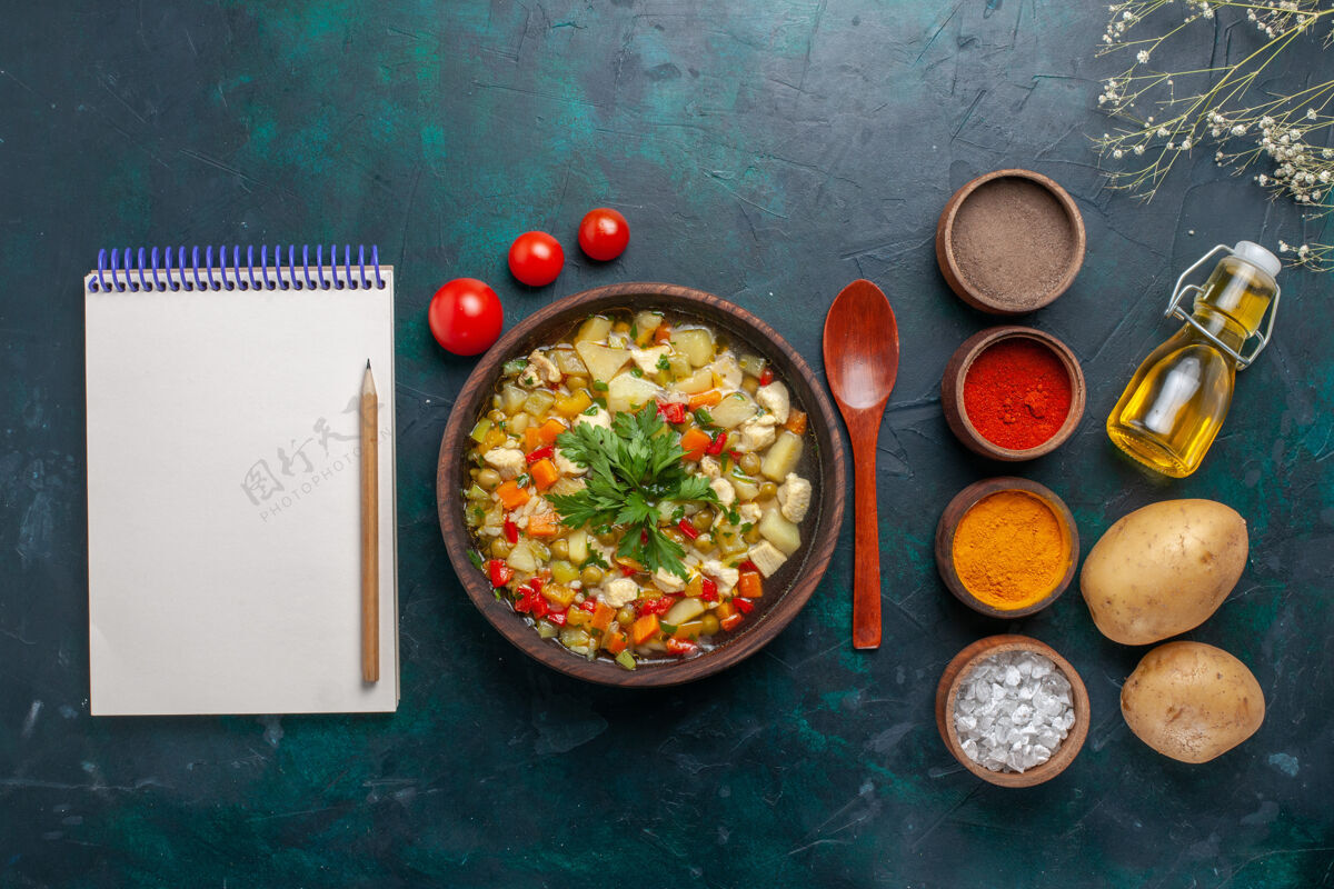 不同俯瞰美味的蔬菜汤与橄榄油记事本和不同调味料上的深色背景配料蔬菜汤色拉油视图容器橄榄