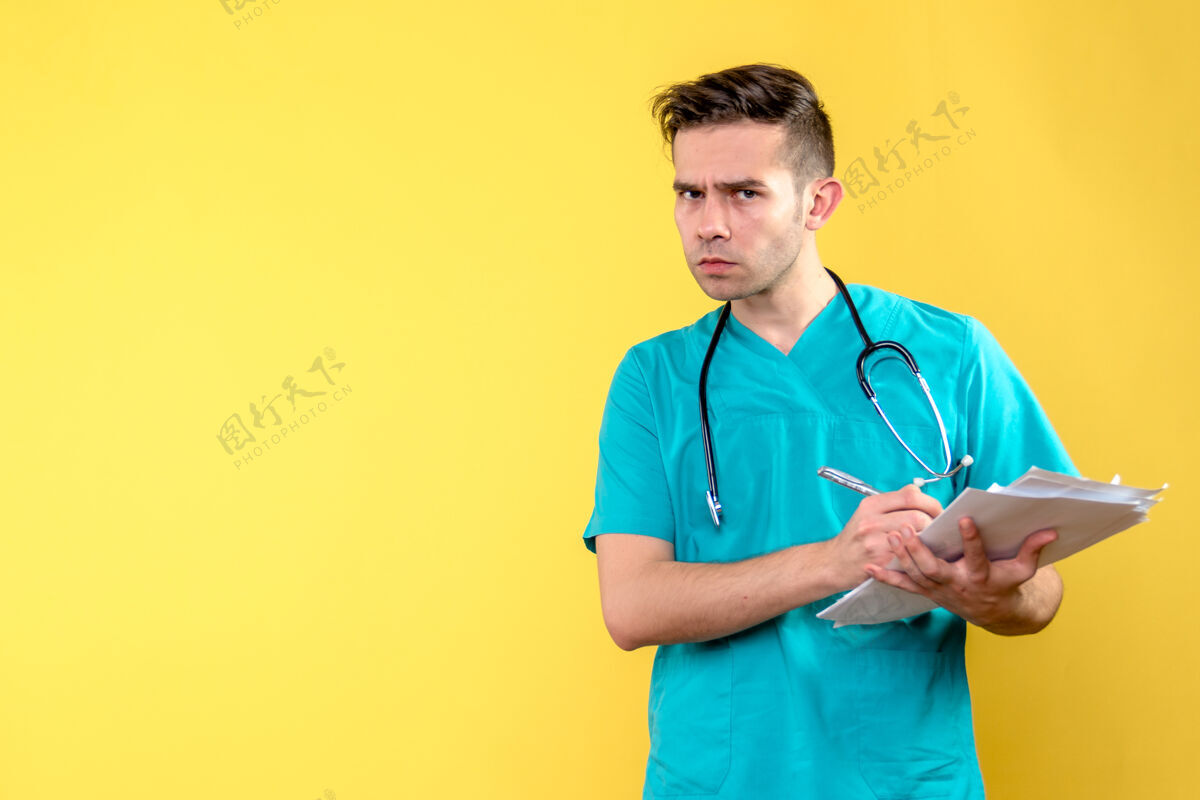 文件黄色墙上有文件的男医生的正视图制服医院黄色