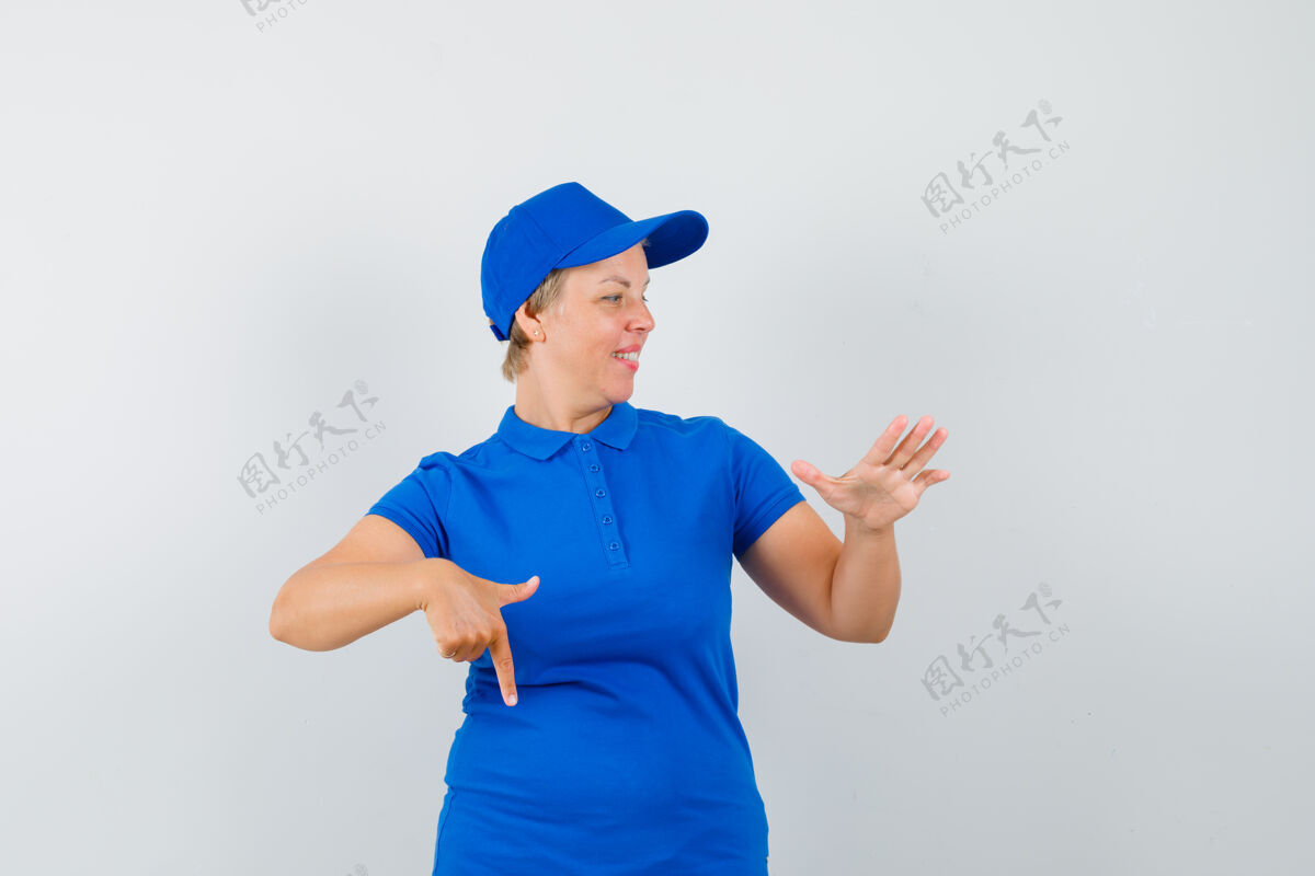 看成熟的女人指着下面 举手穿蓝色t恤 看起来很高兴欢快帽子女人