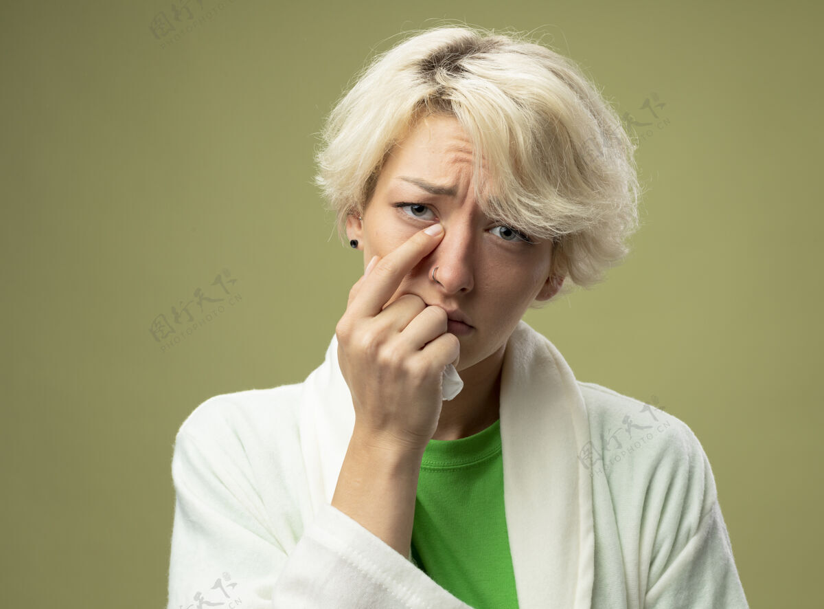 指尖有病的不健康的女人 短发不舒服 手指着鼻子站在光墙上不开心感觉不健康手指