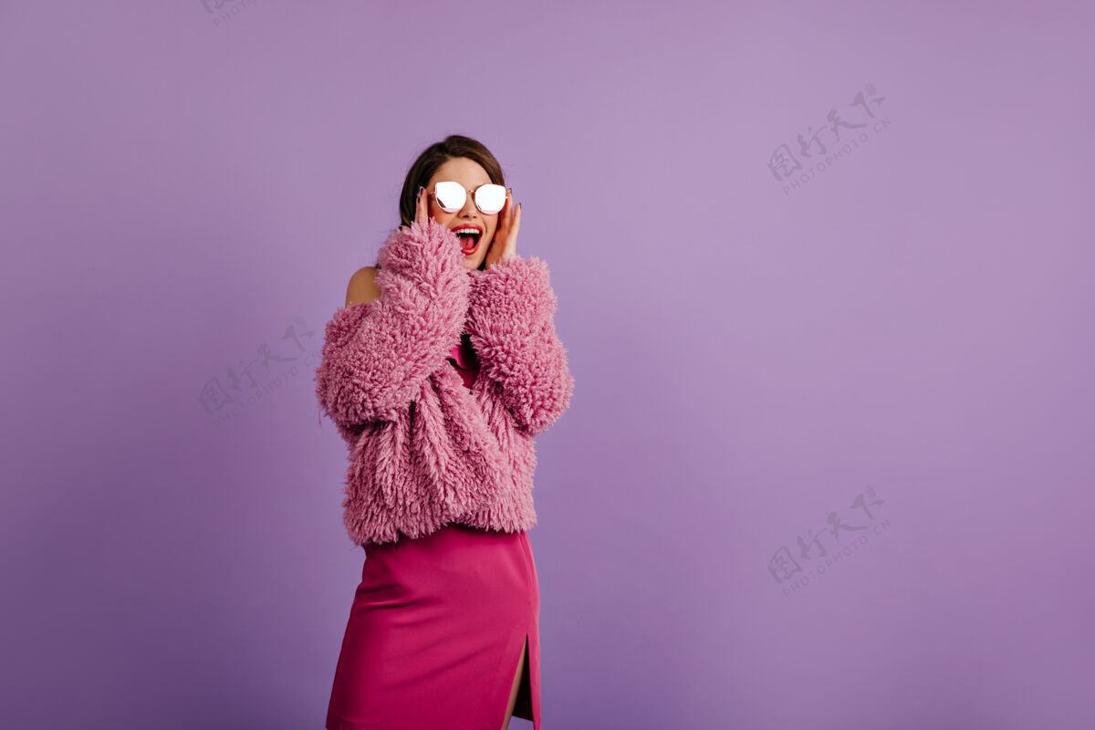 人有趣的女人在紫罗兰墙上情绪化地摆姿势表情女人休闲